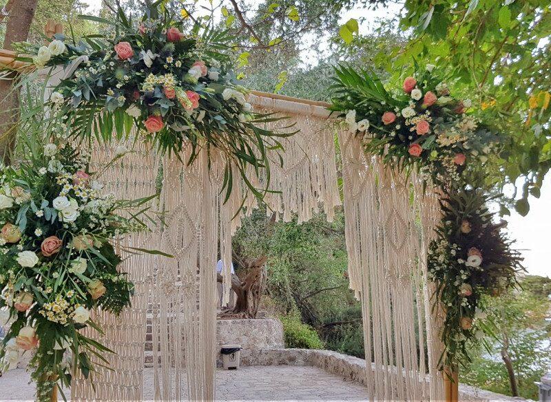 Wooden arch with four pink and white flower bouquets and hanging macrame