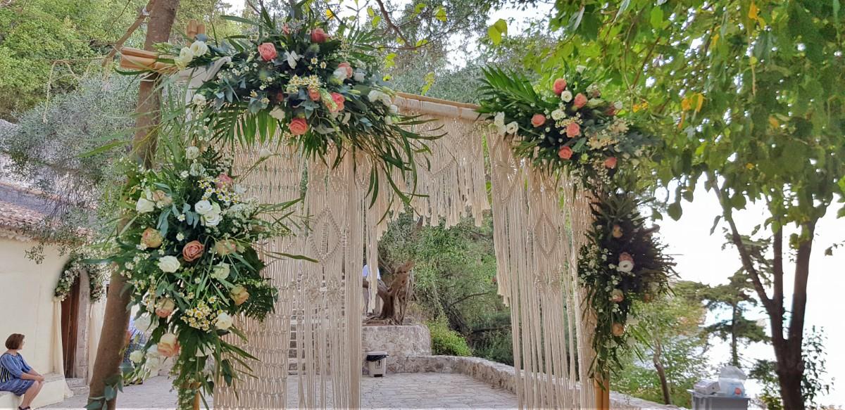 Wooden arch with four pink and white flower bouquets and hanging macrame